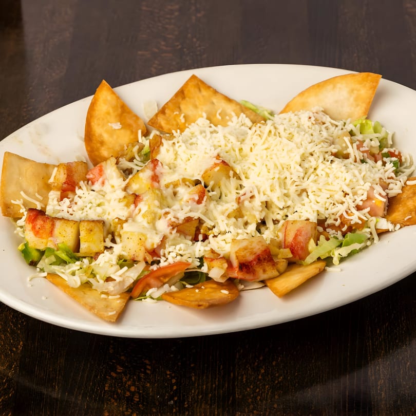 Toro Loco's Mexican salad with chicken, lettuce, tomatoes, cheese, and tortilla chips on a white plate.