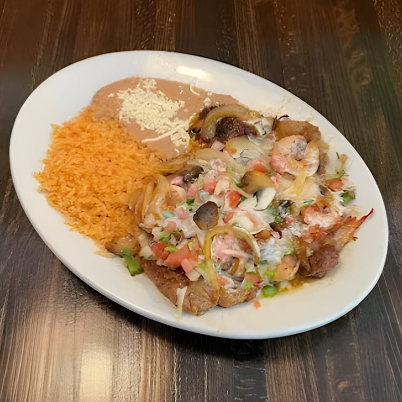 A Mexican dish with shrimp, mushrooms, onions, and tomatoes, served with rice and refried beans.