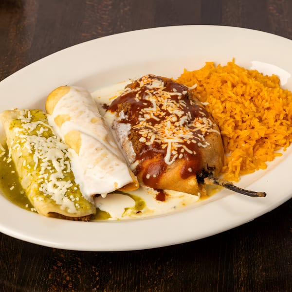 A white plate holds two enchiladas, a chile relleno, and a side of orange rice.
